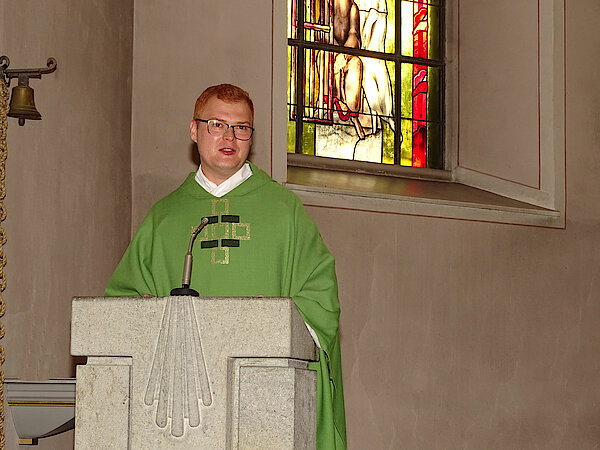 Kaplan Leon Pista stellt sich in St.Petrus in Ketten in Hellenhahn-Schellenberg in einem Primiz-Gottesdienst vor. Symbolisch im Hintergrund Teile des ‚Petrus-Fensters‘ im Chorraum.